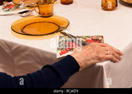 Il vecchio donna seduta e tenendo la mano sul tavolo Foto Stock