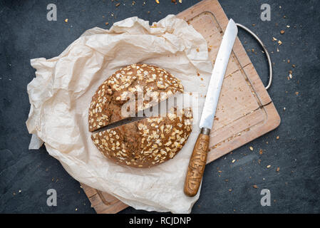 Luce di pane di segale con un vintage Coltello per pane su una scheda di pane Foto Stock