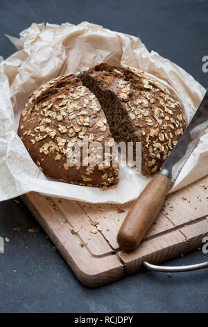 Luce di pane di segale con un vintage Coltello per pane su una scheda di pane Foto Stock