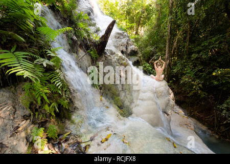 Tropical sessione di yoga da una bella cascata appiccicosa vicino a Chiang Mai nel nord della Thailandia. Namaste, Meditazione - lotus pongono - padma asana Foto Stock