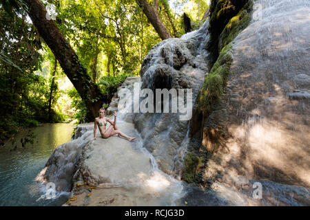 Tropical sessione di yoga da una bella cascata appiccicosa vicino a Chiang Mai nel nord della Thailandia. Ardha Matsyendrasana, mezza torsione spinale Foto Stock