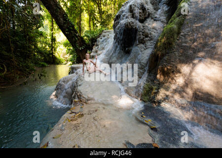 Tropical sessione di yoga da una bella cascata appiccicosa vicino a Chiang Mai nel nord della Thailandia. Ardha Matsyendrasana, mezza torsione spinale Foto Stock