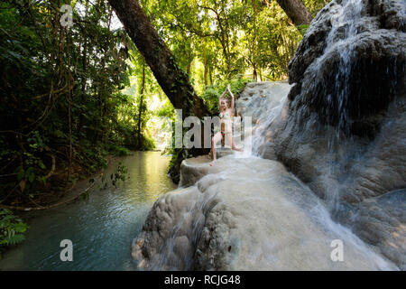 Tropical sessione di yoga da una bella cascata appiccicosa vicino a Chiang Mai nel nord della Thailandia. Posa del guerriero - Virabhadrasana Foto Stock