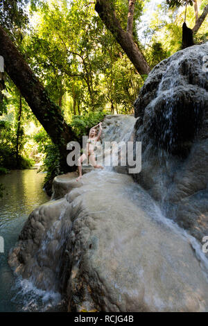 Tropical sessione di yoga da una bella cascata appiccicosa vicino a Chiang Mai nel nord della Thailandia. Posa del guerriero - Virabhadrasana Foto Stock