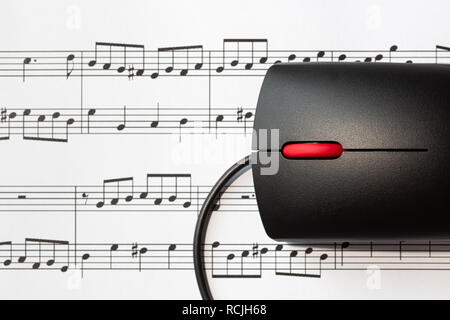 Il mouse del computer su un foglio con le note musicali, close-up con il fuoco selettivo. Il concetto di digitalizzazione di musica Foto Stock