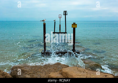 Paesaggio fotografia scattata dalla fine della spiaggia groyne a barene, Poole, di marcatori di avvertimento sulla struttura sommersa. Foto Stock