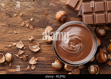 Cioccolato da spalmare con le nocciole su sfondo di legno Foto Stock