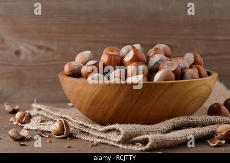 Le nocciole in ciotola di legno su sfondo di legno Foto Stock