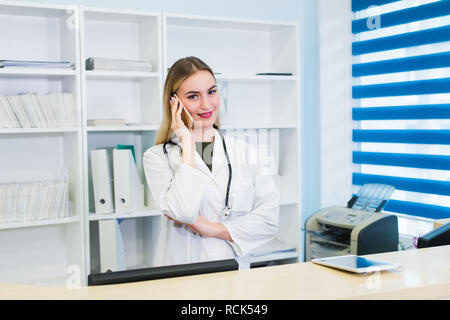 Giovane bella donna dottore parlando al telefono in ufficio Foto Stock