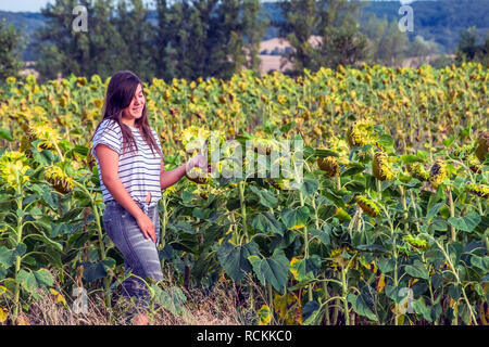 Giovane ragazza sorridente in un campo di girasoli Foto Stock