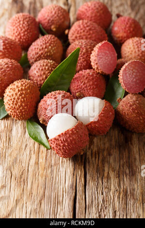 Il Lychee frutti con foglie verdi di close-up su di un tavolo di legno. verticale, stile rustico Foto Stock