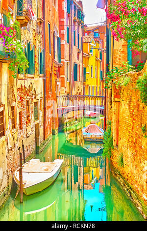 Canale veneziano con un piccolo ponte e barche ormeggiate sulla soleggiata giornata estiva, Venezia, Italia Foto Stock