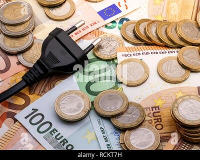 Immagine di una spina di alimentazione in euro e monete in denaro e fatture suggerendo una modifica dell'alimentatore close up Foto Stock