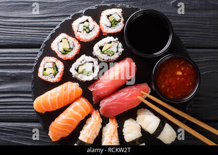 Set di fresco, maki uramaki e nigiri sushi, servita su piastra nera di close-up. Parte superiore orizzontale vista da sopra Foto Stock