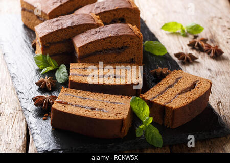 Fette di torta polacca piernik con confettura di prugne close-up su una scheda di ardesia sul tavolo orizzontale. Foto Stock