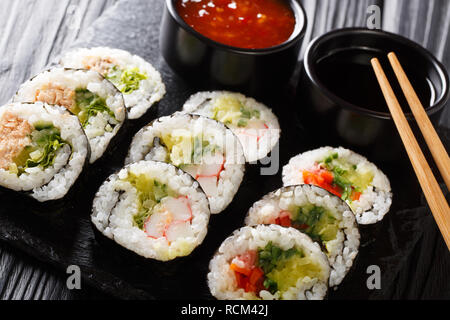 Set di rulli giapponese futomaki con soia e salse close-up su una scheda di ardesia sul tavolo orizzontale. Foto Stock