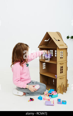 Felice bambina gioca con cartone casa di bambola. Funny bel bambino si diverte a. Foto Stock