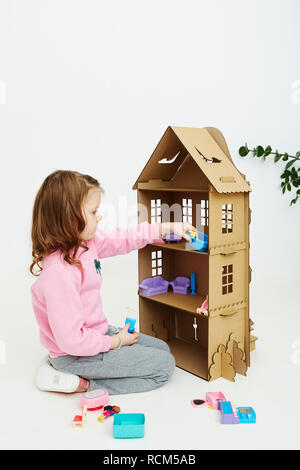 Felice bambina gioca con cartone casa di bambola. Funny bel bambino si diverte a. Foto Stock