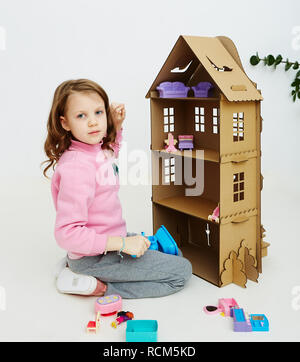 Felice bambina gioca con cartone casa di bambola. Funny bel bambino si diverte a. Foto Stock