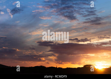 Alba nel campo. Nuvole tinti in colori caldi durante il sunrise. Ora d'oro. Foto Stock