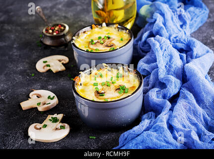 Funghi cotti al forno con julienne di pollo e formaggio in pentole. Foto Stock