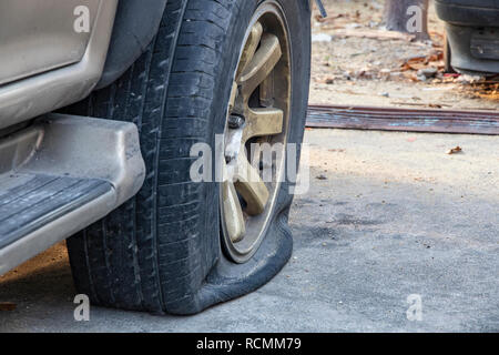 Close-up di danneggiato il pneumatico sgonfio di auto in parcheggio. Foto Stock