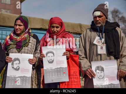 Srinagar, India. 15 gennaio, 2019. I membri di APDP visto tenendo premuto rilasciato i calendari e le fotografie della loro scomparsa cari durante una manifestazione di protesta a Srinagar.Per mantenere la ricerca di persone scomparse in vita, l'Associazione dei Genitori di Persone scomparse (APDP) rilascia 2019 calendario durante una manifestazione di protesta a Srinagar. I documenti del calendario le storie di rapimenti, con ogni mese la pagina che porta una foto di una persona che è scomparso in quel mese. Il calendario è dotato anche di poesia di molti poeti rivoluzionario. Secondo APDP oltre 8000 Kashmiris sono scomparse dal 1989. (Cre Foto Stock