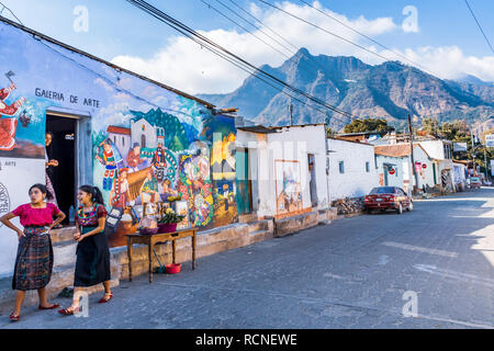 San Juan la Laguna, lago Atitlan, Guatemala - Dicembre 31, 2018: Maya le donne in abiti tradizionali, murale street & Indiana naso parco nazionale di dietro. Foto Stock
