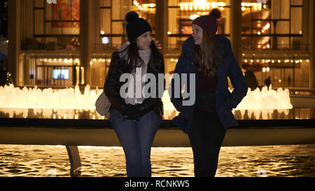 Due ragazze hanno una fantastica notte di New York mentre è seduto a una fontana Foto Stock