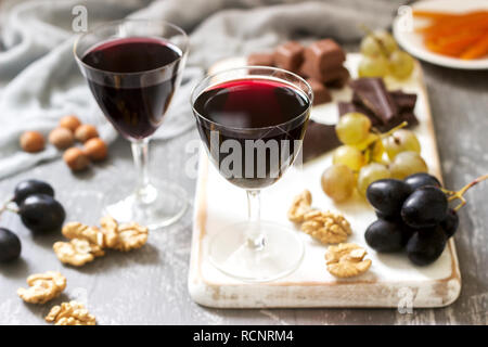 Crème de Cassis liquore casalingo servita con uve, noci e cioccolato. In stile rustico, il fuoco selettivo. Foto Stock