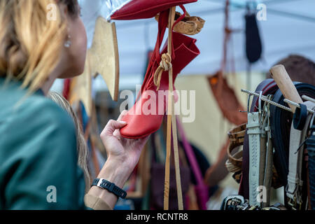 Una donna nel mercato di artigianato guarda al red shoes. - Immagine Foto Stock