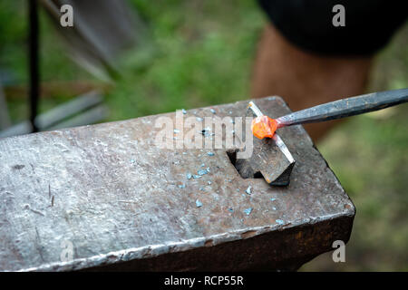 Il fabbro forgiato una striscia di metallo caldo. close up - Immagine Foto Stock