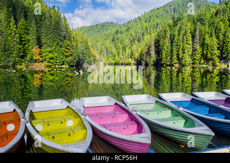 Colorate barche ormeggiate su un lago di montagna, verde foresta in mirroring del lago. Diga naturale lago nella foresta, Lago Rosso in Romania Foto Stock
