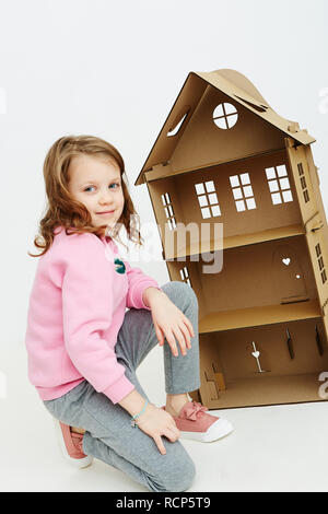 Felice bambina gioca con cartone casa di bambola. Funny bel bambino si diverte a. Foto Stock