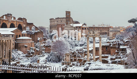 Congelati Roma. Vista del Foro Romano le antiche rovine e il Coliseum coperte da neve Foto Stock