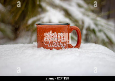 Tazza calda con vapore rising rilassarsi più preoccuparsi meno messaggio circondato da scena nevoso e gelido rami di pino in inverno sfondo, stress vacanza di mantenere la calma Foto Stock