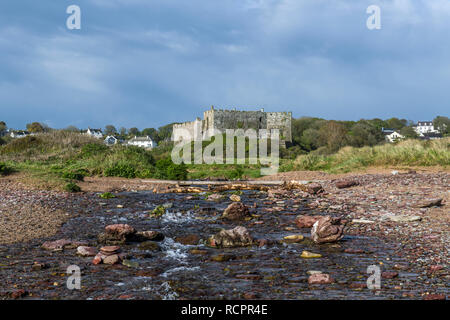 Manorbier Castle e sulla spiaggia di South Pembrokeshire costa nel Galles occidentale con un fiume in primo piano Foto Stock