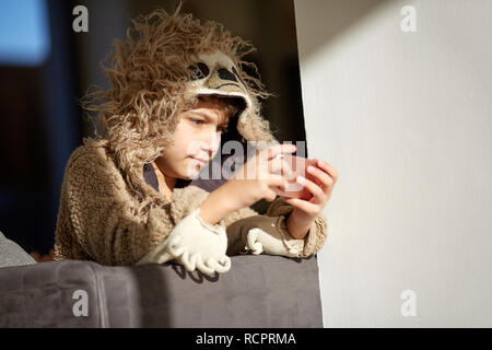 Ragazzo in bradipo pigiami riproduzione cellulare Foto Stock