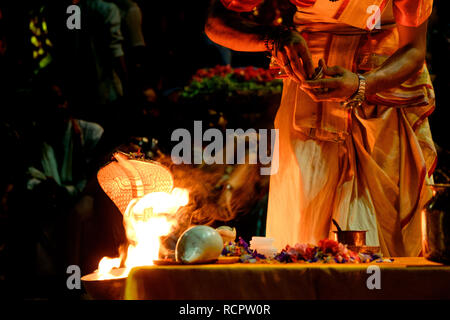 Chiusura del giovane sacerdote Indù esecuzione rituale giornaliero ganga aarti cerimonia con fuoco e serpente simbolico Foto Stock