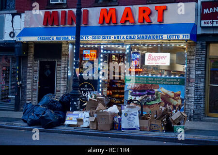 Garbage impilati al di fuori sul marciapiede a Brooklyn, New York, accanto a un negozio al dettaglio Foto Stock