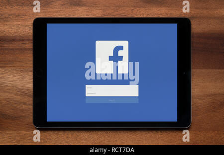 La schermata di accesso di Facebook è visto su un tablet iPad, il quale è appoggiato su un tavolo di legno (solo uso editoriale). Foto Stock