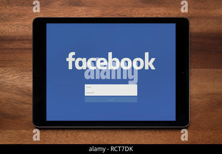 La schermata di accesso di Facebook è visto su un tablet iPad, il quale è appoggiato su un tavolo di legno (solo uso editoriale). Foto Stock