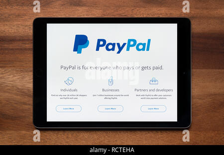 Il sito web di PayPal è visto su un tablet iPad, il quale è appoggiato su un tavolo di legno (solo uso editoriale). Foto Stock