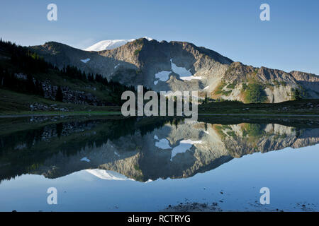 WA15786-00...WASHINGTON - la vetta del Monte Rainier a picco sul Crescent Mountain e riflettendo in un lago alla base della cresta Tyee nei pressi di Windy Gap Foto Stock