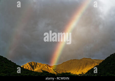 Doppio arcobaleni sopra Boyle Flat capanna a sunrise, St James passerella, Nuova Zelanda. Foto Stock