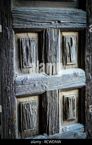 Primo piano di una vecchia porta in legno intagliata a mano, usurata e polverosa, vintage e con intemperie Foto Stock