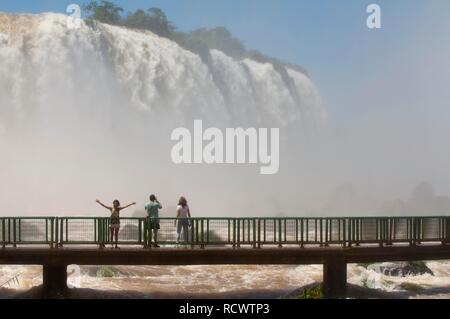 I turisti in una passerella di fronte all'Iguazu o Iguaçu falls, lato Brasiliano, Unesco Parco Nazionale, Provincia Misiones Foto Stock