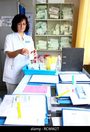 L'infermiera preparare i documenti e medicina per pazienti in della postazione dell'infermiera di un ospedale Foto Stock