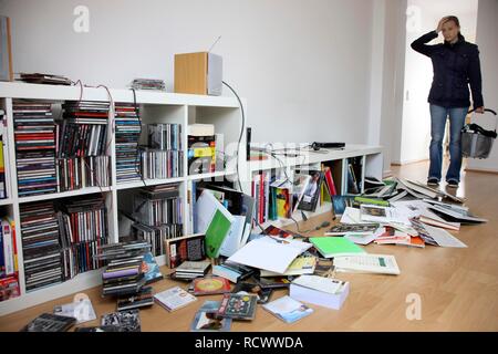 Giovane donna alla scoperta della scena di un furto con scasso, saccheggiato ripiano Foto Stock