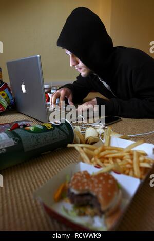 Hacker che lavora su un computer portatile in uno scarsamente appartamento ammobiliato, immagine simbolica per la pirateria informatica, criminalità informatica Foto Stock